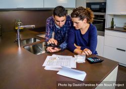 Couple reviewing their monthly bills on kitchen counter 4dpPl4