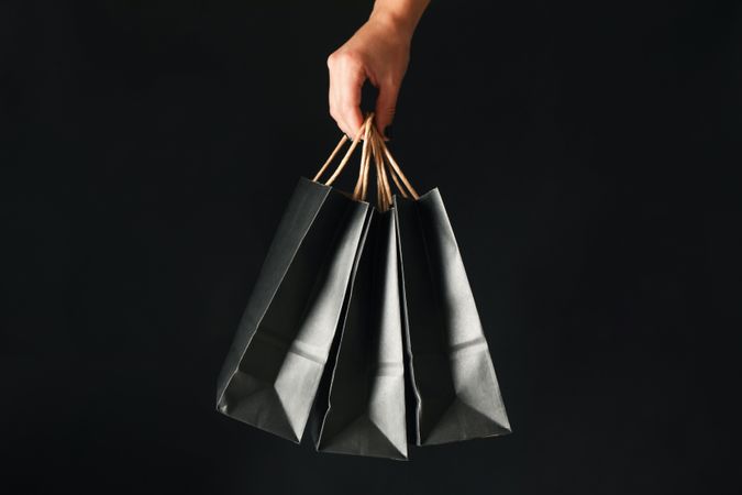 Female hand hold paper bags on dark background
