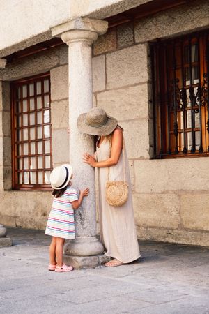 Mother and daughter walking in street along ancient building