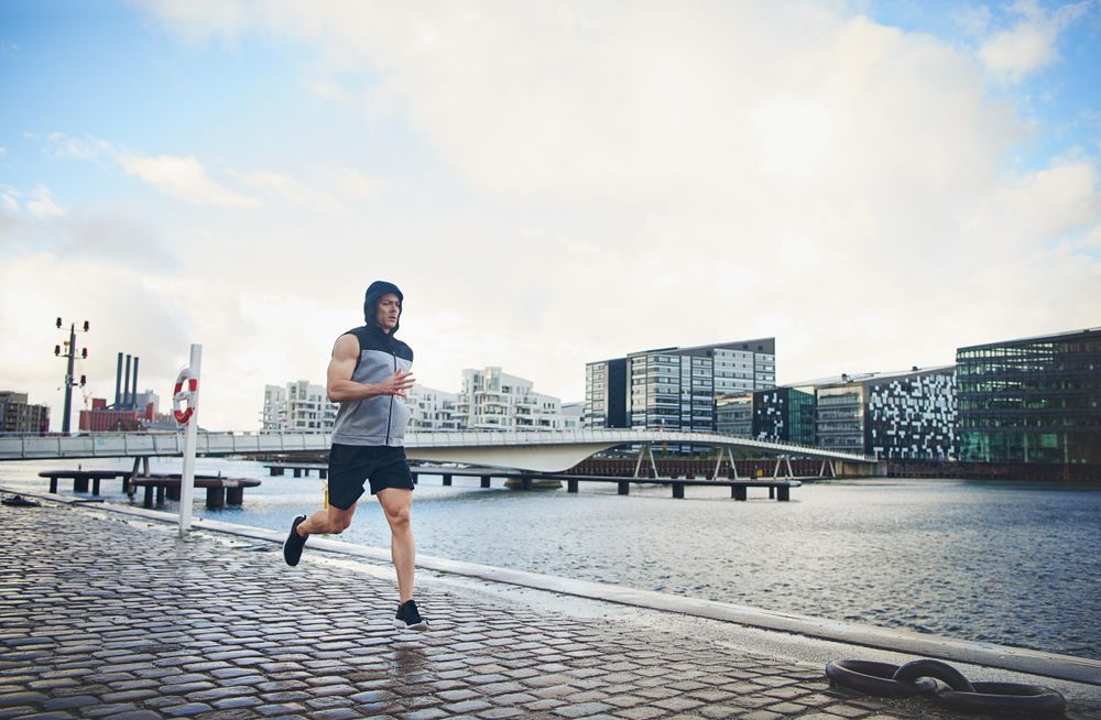 Man in vest running outside near river