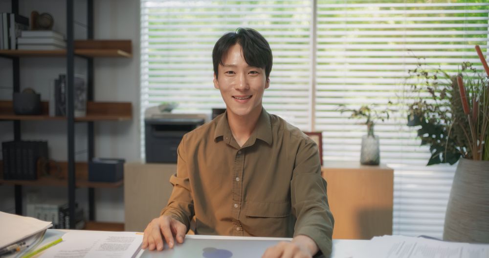 Portrait of a South Korean Male Working on a Computer Behind a Desk in a Stylish Creative Agency.