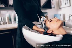 Close up of hairdresser washing customer’s hair in salon sink 4m7jz0