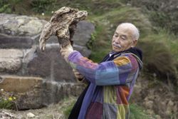Grey haired man breaking stone formation