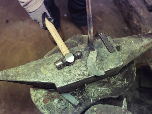 Crop forger working on anvil with hammer and sickle