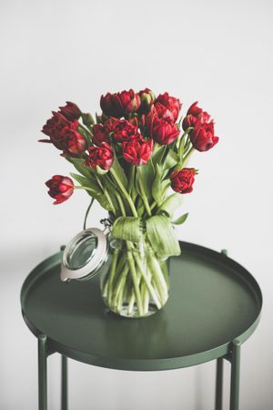 Vase of red tulips on green table