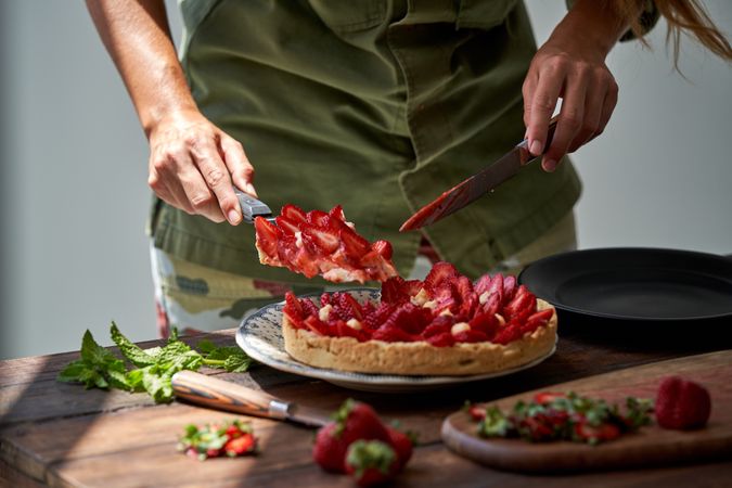 Faceless cook serving strawberry cake