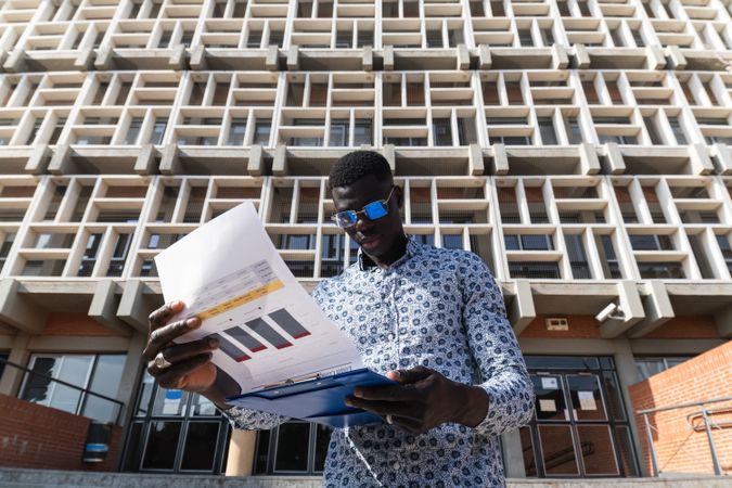 Black businessman with documents on clipboard in city