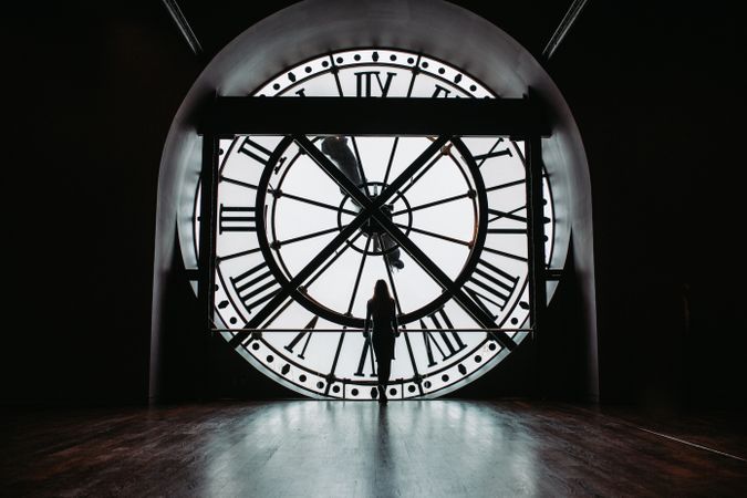 Silhouette of woman standing inside round analog clock
