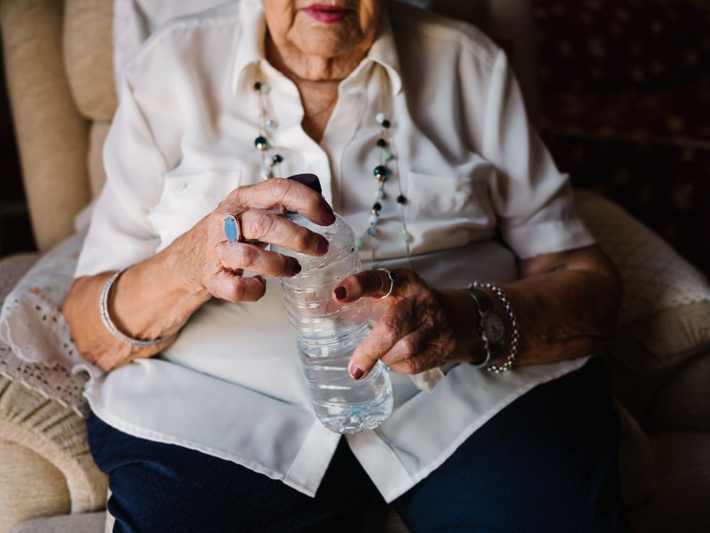 Mature female drinking medicines with water at home