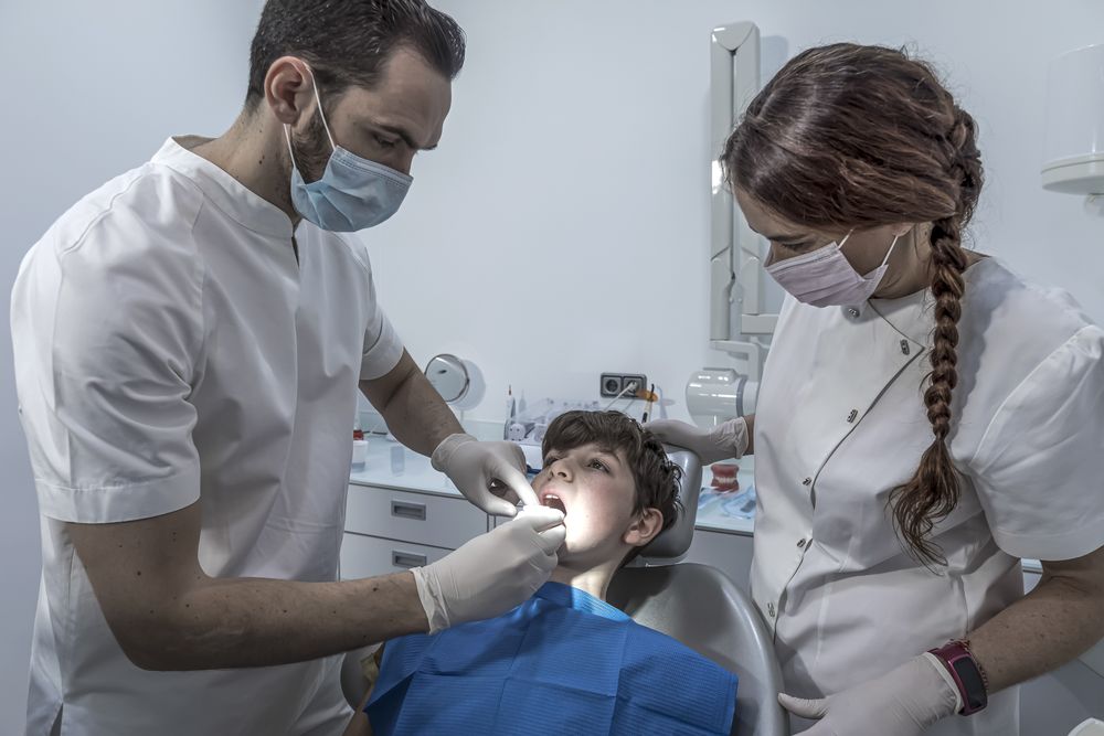 Dentist examining little boy's teeth in clinic
