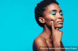Close up of young female model with vibrant makeup against blue background 5lmj64