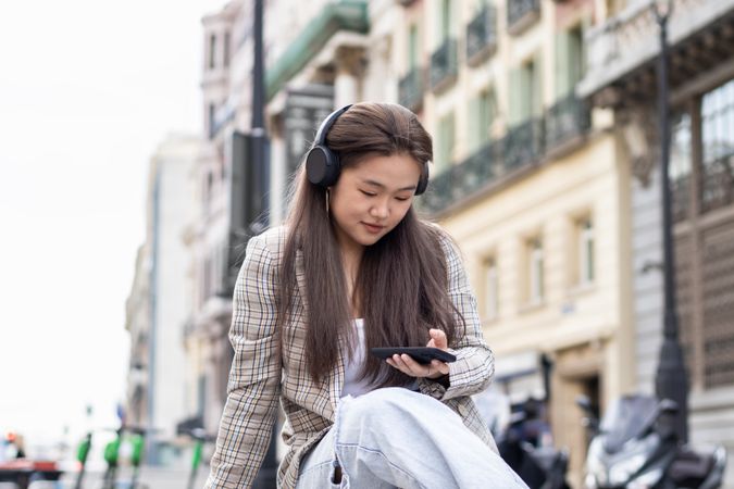 Young Asian woman listening to music with smartphone in the city