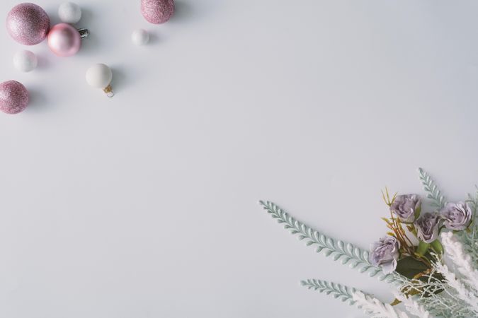 Pink baubles and flowers with snowy leaves in corners of light background