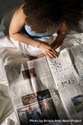 Top view of woman with curly hair reading newspaper 56EaN0