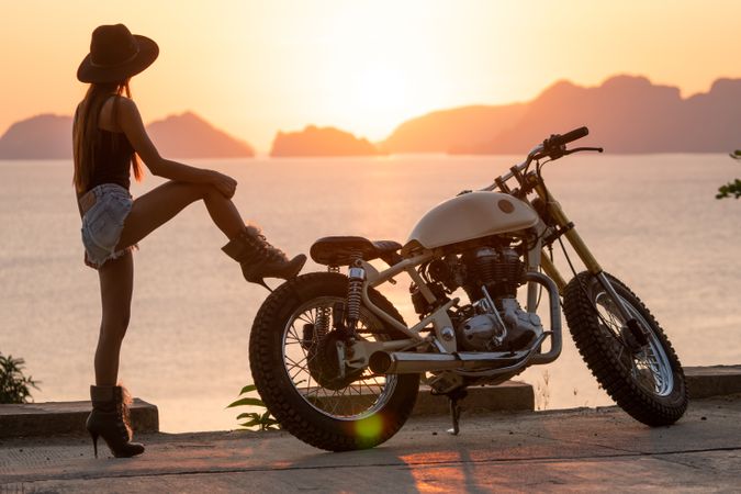 Woman tying boots near motorcycle