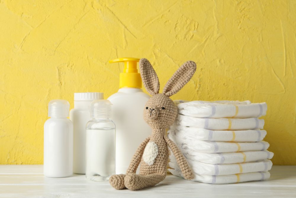 Baby hygiene accessories on wooden table against yellow background