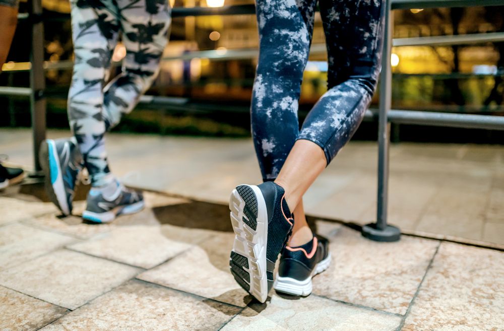 Close up of legs of female runners resting after training at night on town