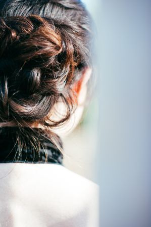 Close up cropped shot of woman’s head with hair bun style and brunette hair