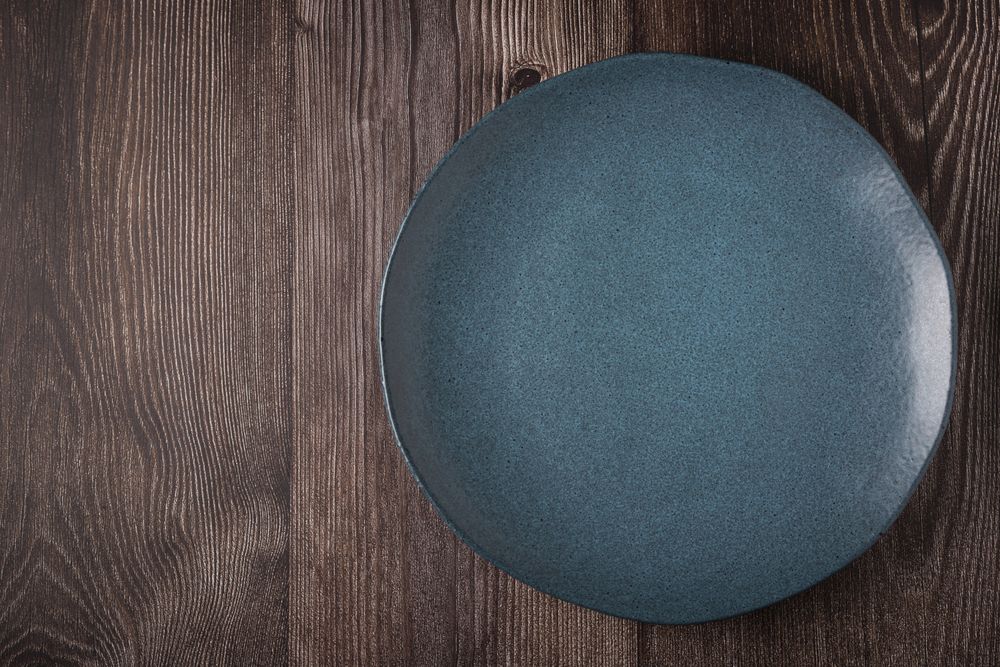 Empty plate on the wooden table. Top view of the image.