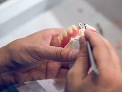 Crop dental technician carving denture