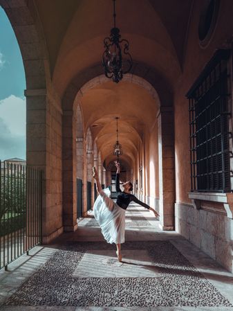 Gracious female ballet dancer raising leg in arched passage