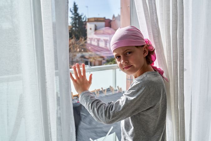 Boy in pink bandana against balcony door