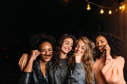 Multi-ethnic group of women joking around outside at night