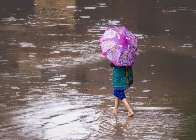 Girl holding an umbrella and walking on shallow water