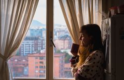 Woman enjoying hot beverage near fridge