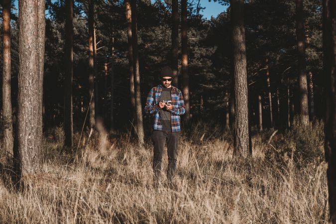 Confident photographer taking picture with camera in sunny forest
