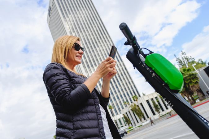 Woman browsing smartphone and riding electric scooter