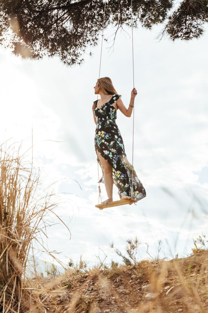 Happy female enjoying on a swing at sunset