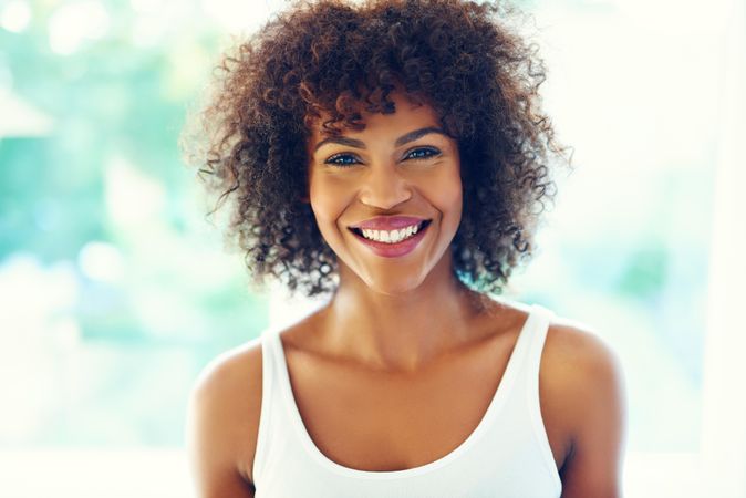 Portrait of smiling female with curly hair on leafy background