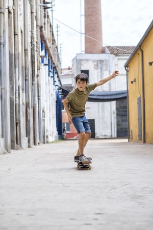 Front view of cheerful skater boy riding on through street