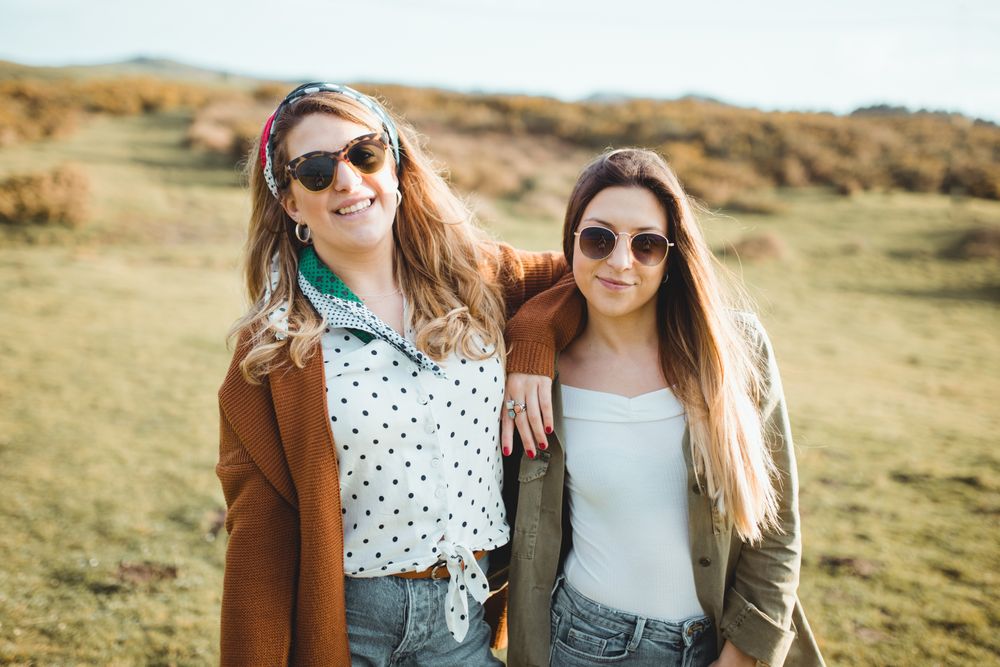Stylish cheerful women standing on green field
