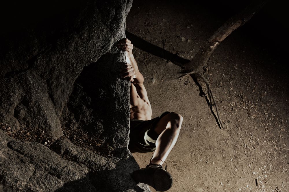 Man practicing rock climbing among large rocks in a forest