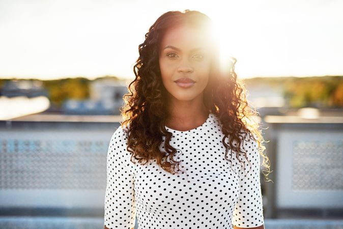 Radiant Black woman on sunny roof and dotted shirt