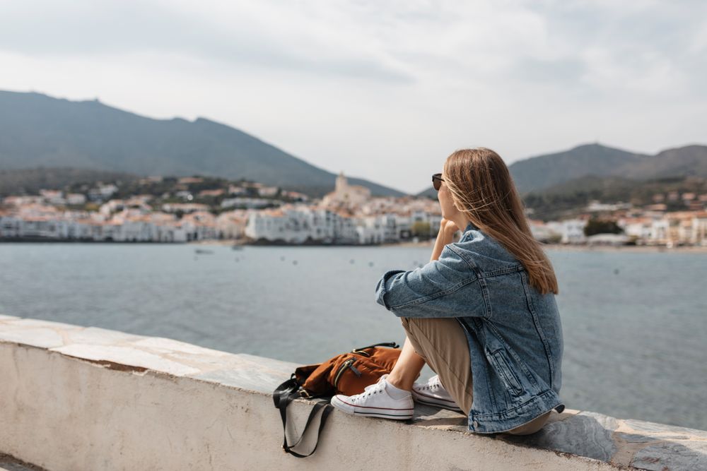 Woman sitting on ledge near the water talking on a smartphone