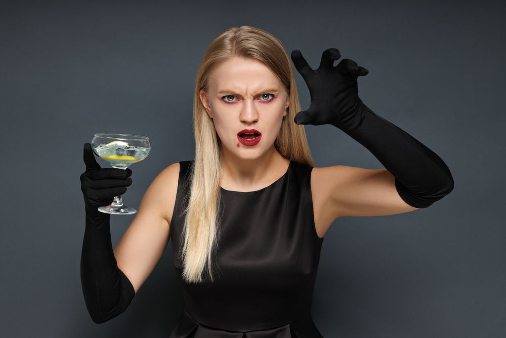 A woman at a party in the style of Halloween with a cocktail in her hands