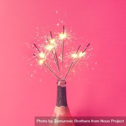 Champagne bottle with sparklers on pink background 0ywx14