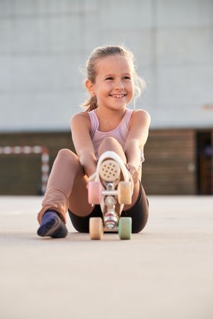 Content girl preparing for roller skating in city street