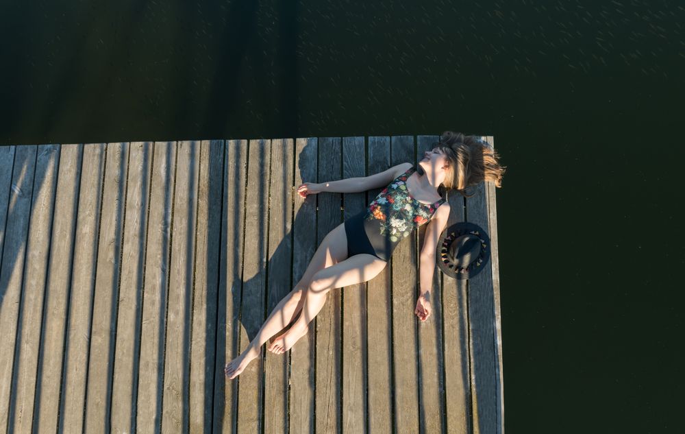 Young female lying down on pier on nature