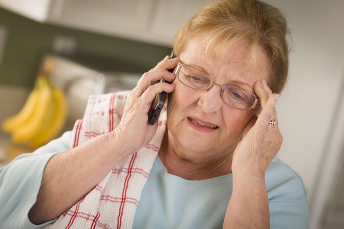 Shocked Older Adult Woman on Cell Phone in Kitchen