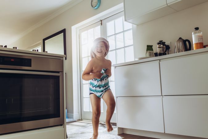 Cheerful kid in bath clothes running at home