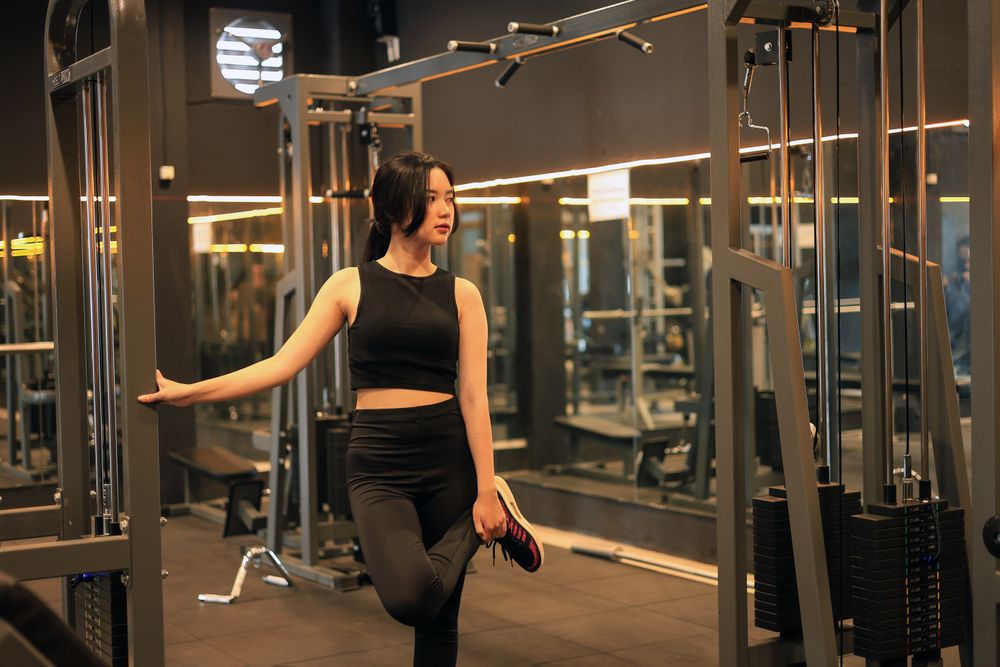 Young Woman Doing Stretching Exercise before Workout at the Gym