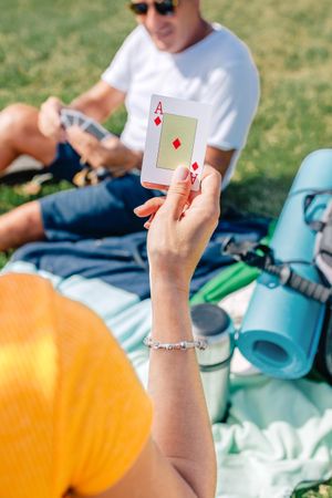 Back of woman holding up ace of diamonds card on picnic