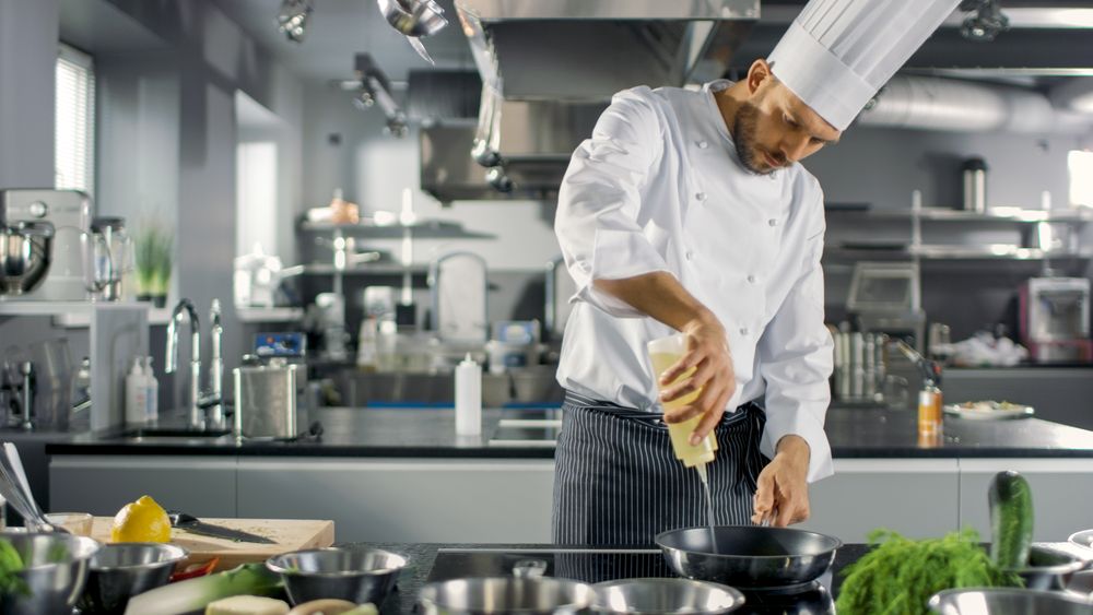 Professional Chef Working in a Famous Restaurant Kitchen. Starts Preparing His Specialized Dish, Turns on Stove and Puts Pan with Oil on it.