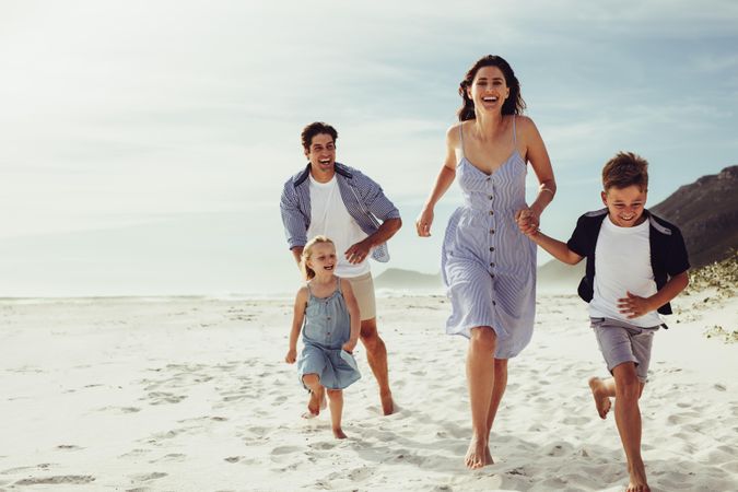 Family of four running together on the sea shore