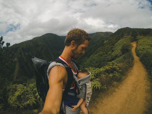 Father with backpack holding baby in mountain