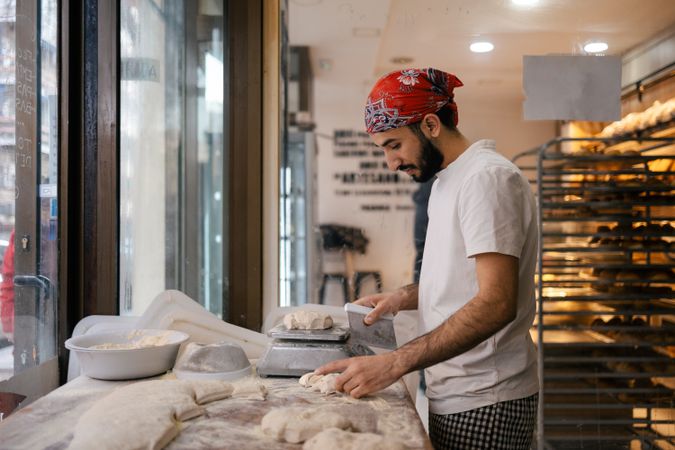 Arabic baker cutting dough with scapula